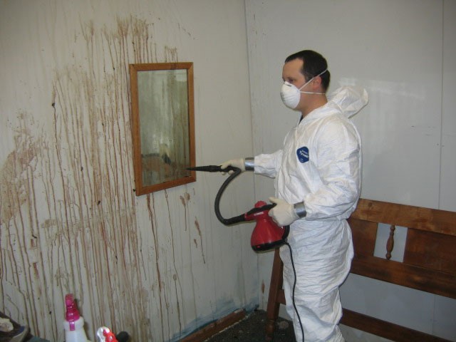 Un nettoyeur qui nettoie avec une machine un mur rempli de sang